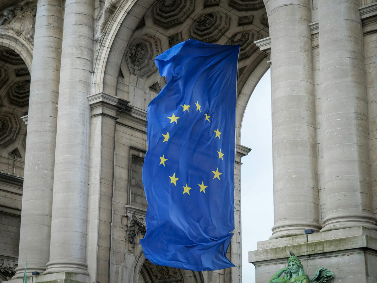 European Union flag hanging from an archway in an urban setting